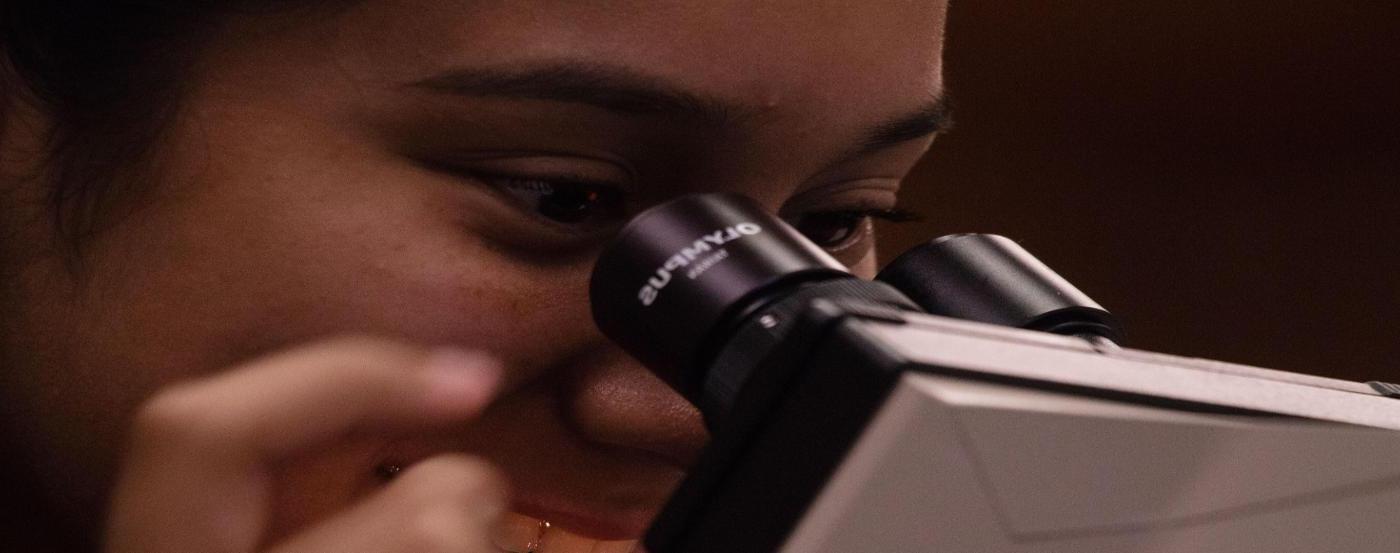 PGCC student smiling while looking into microscope